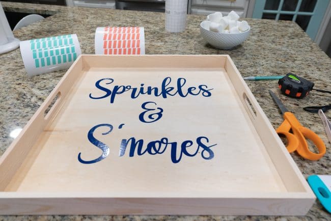Wood tray with dark blue vinyl applied reading Sprinkles & S'mores